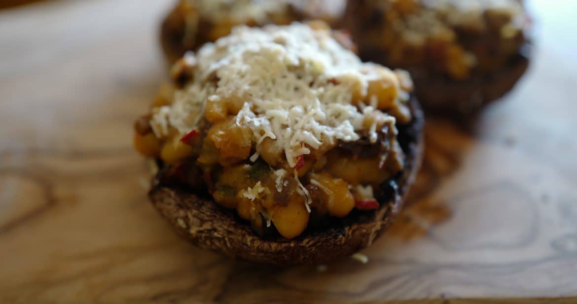 Close up stuffed portobello vegetarian cap filled with sun-dried tomatoes, sprinkled with Pecorino cheese, by Foodjoya