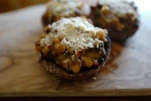 Close up stuffed portobello vegetarian cap filled with sun-dried tomatoes, sprinkled with Pecorino cheese, by Foodjoya