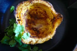 Roasted acorn squash (winter squash) with spices, avocado oil, served next to cilantro and mint by Foodjoya.