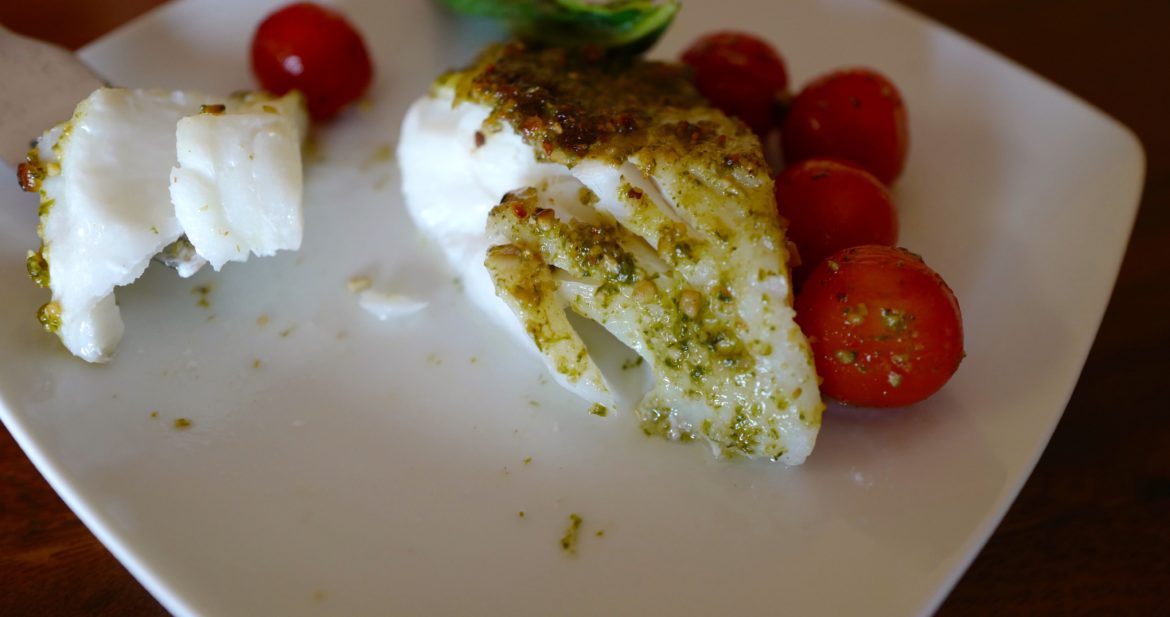 Pesto baked cod cut with a fork by foodjoya
